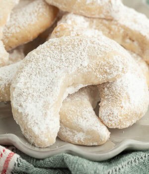 Close up of almond crescent cookies piled on a plate.