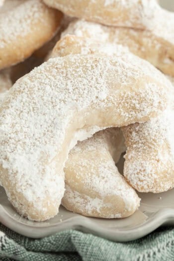 Close up of almond crescent cookies piled on a plate.