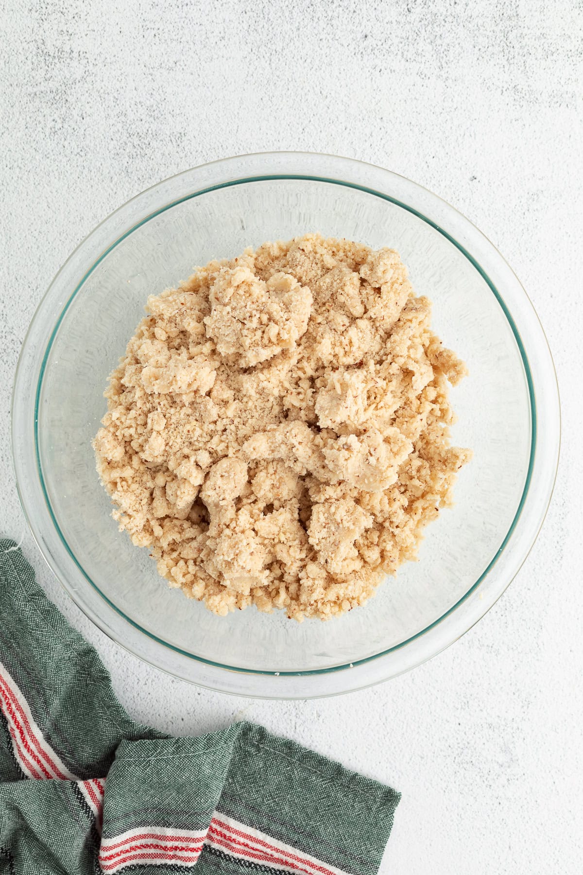 These classic almond crescent cookies have a buttery, crumbly shortbread texture and a sweet powdered sugar coating. No chilling needed! Crumbly cookie dough in a glass mixing bowl.