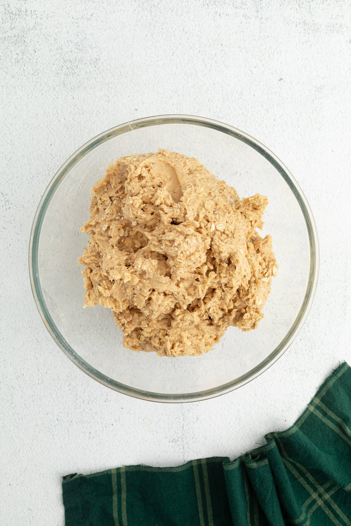 These old-fashioned iced oatmeal cookies have soft middles, crispy edges, and plenty of brown sugar and cinnamon, topped with vanilla icing. Oatmeal cookie dough in a glass mixing bowl.