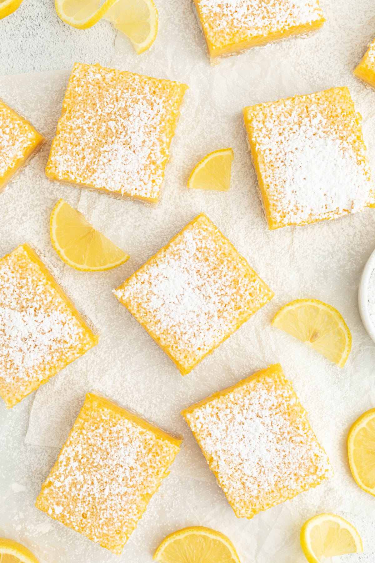 Make the best lemon bars that are perfectly baked with a soft, buttery shortbread crust and a sweet, tangy, creamy lemon curd filling. Overhead view of assorted lemon bars dusted with powdered sugar, next to lemon wedges on a countertop.