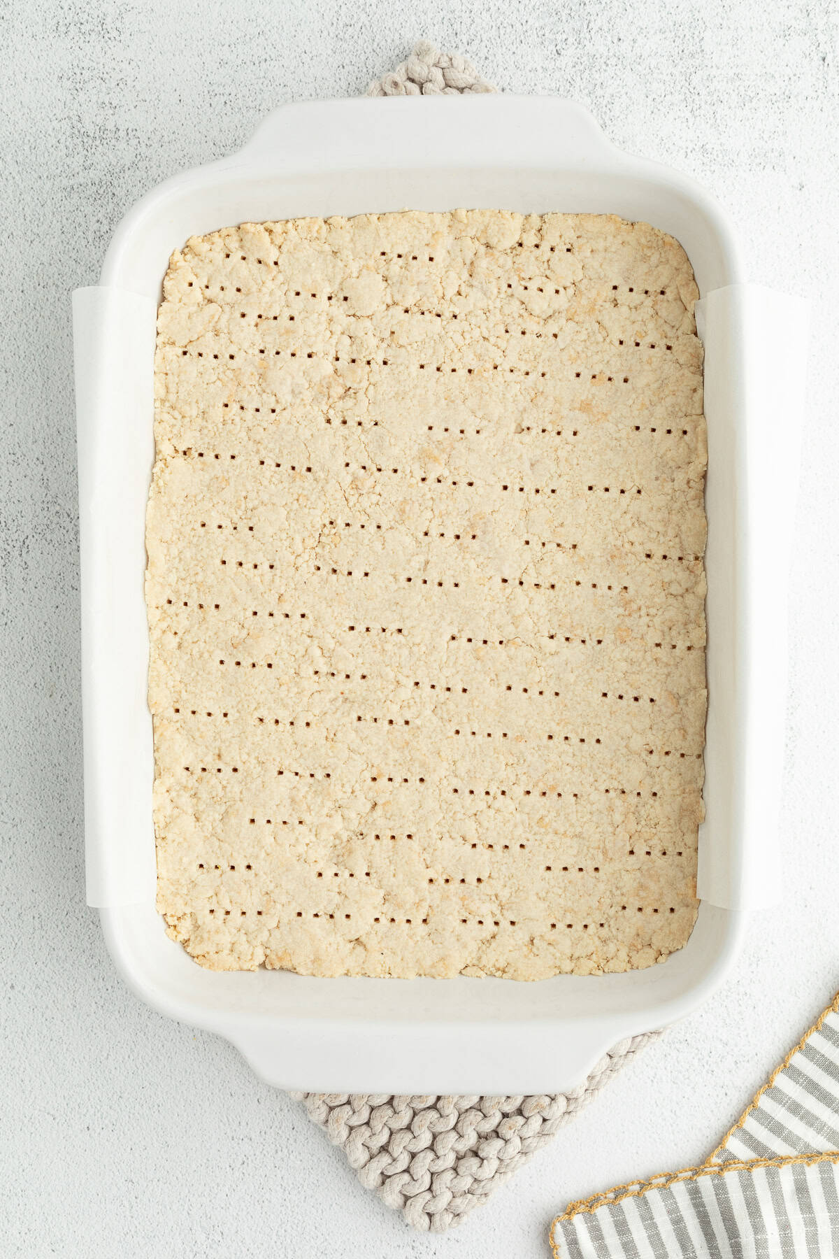 Make the best lemon bars that are perfectly baked with a soft, buttery shortbread crust and a sweet, tangy, creamy lemon curd filling. Par-baked shortbread crust pricked with a fork inside a baking dish.