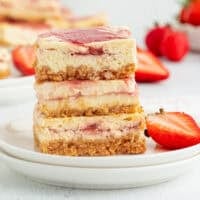 Three strawberry cheesecake bars stacked on a plate.