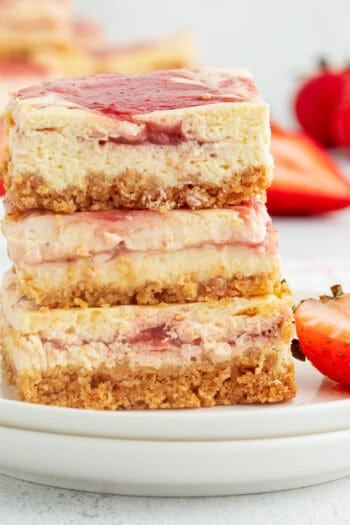 Three strawberry cheesecake bars stacked on a plate.