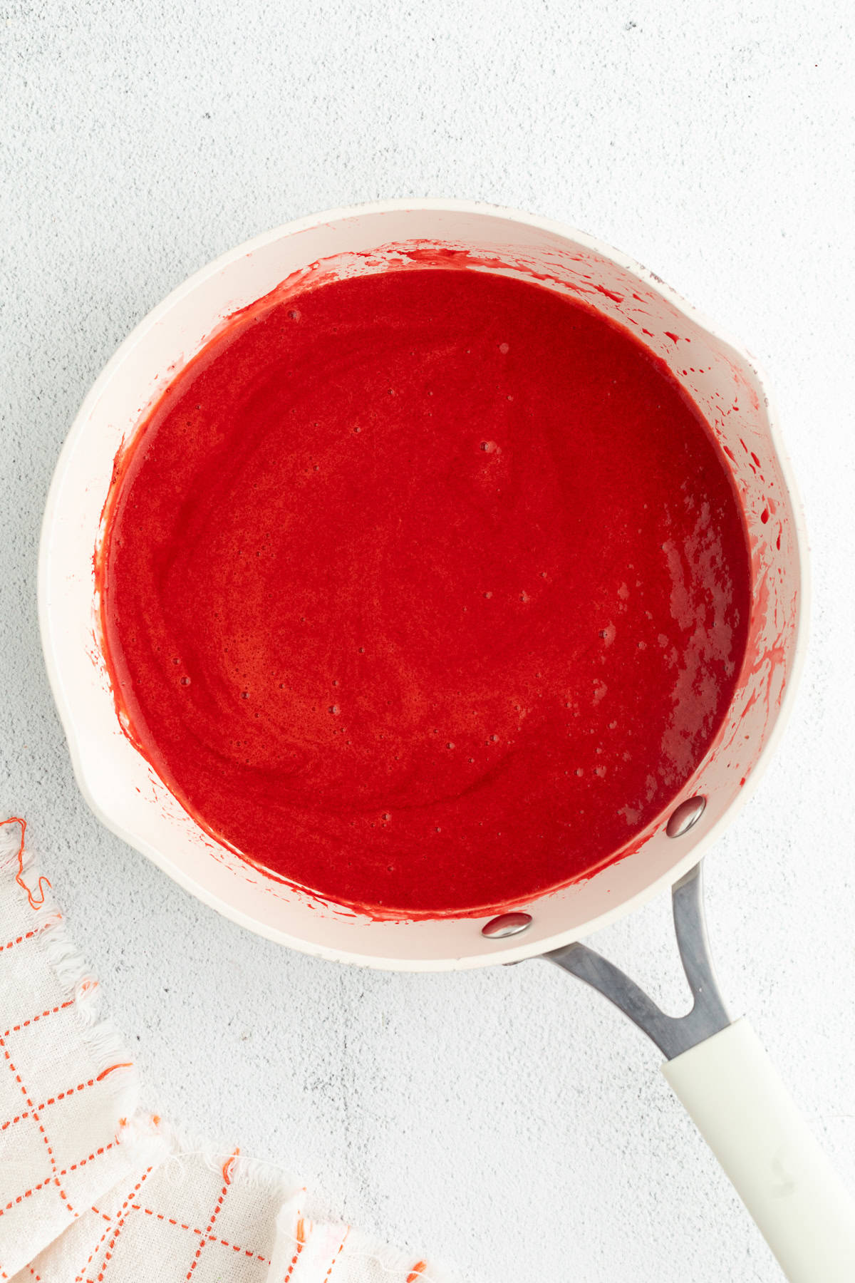 Strawberry cheesecake bars are easier to bake than a classic cheesecake, with a buttery crust and rich filling swirled with strawberry sauce! Strawberry sauce in a saucepan.