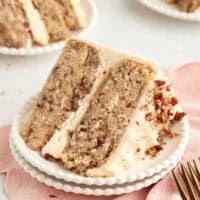 A slice of hummingbird cake with cream cheese frosting on a plate.