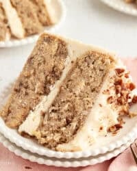 A slice of hummingbird cake with cream cheese frosting on a plate.