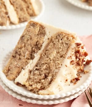 A slice of hummingbird cake with cream cheese frosting on a plate.