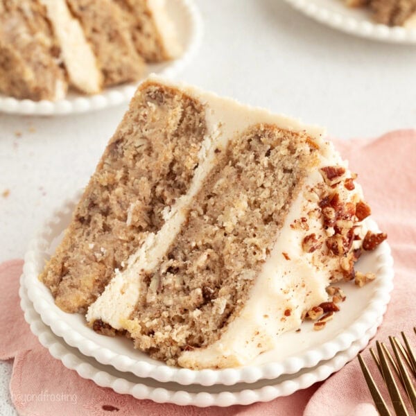 A slice of hummingbird cake with cream cheese frosting on a plate.