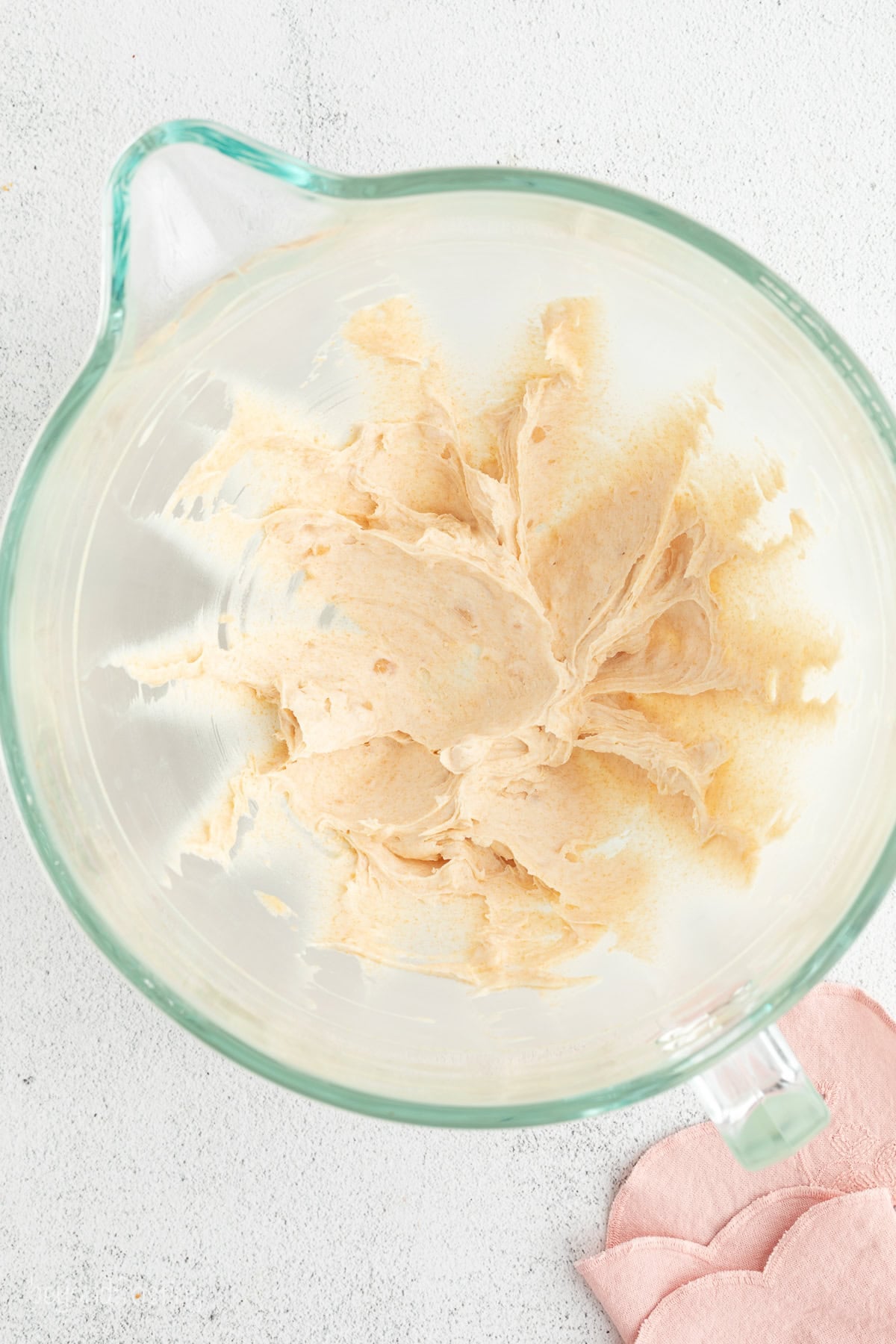 Hummingbird cake is a soft, spiced Southern layer cake with sweet banana, crushed pineapple, crunchy pecans, and cream cheese frosting. Brown butter beaten in a bowl.