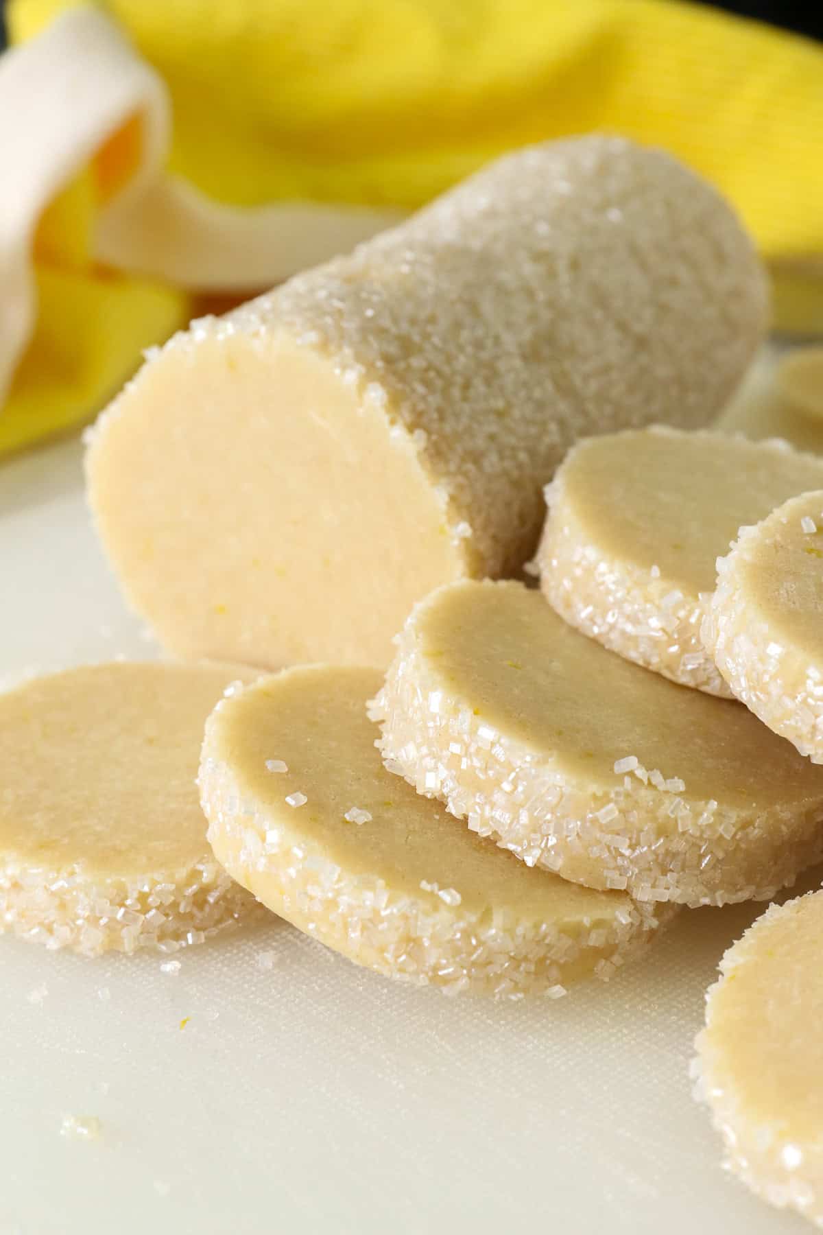 These slice-and-bake lemon shortbread cookies are crisp, buttery, and melt-in-your-mouth, rolled in sanding sugar for sweet, crunchy edges. A log of lemon shortbread cookie dough sliced into rounds.