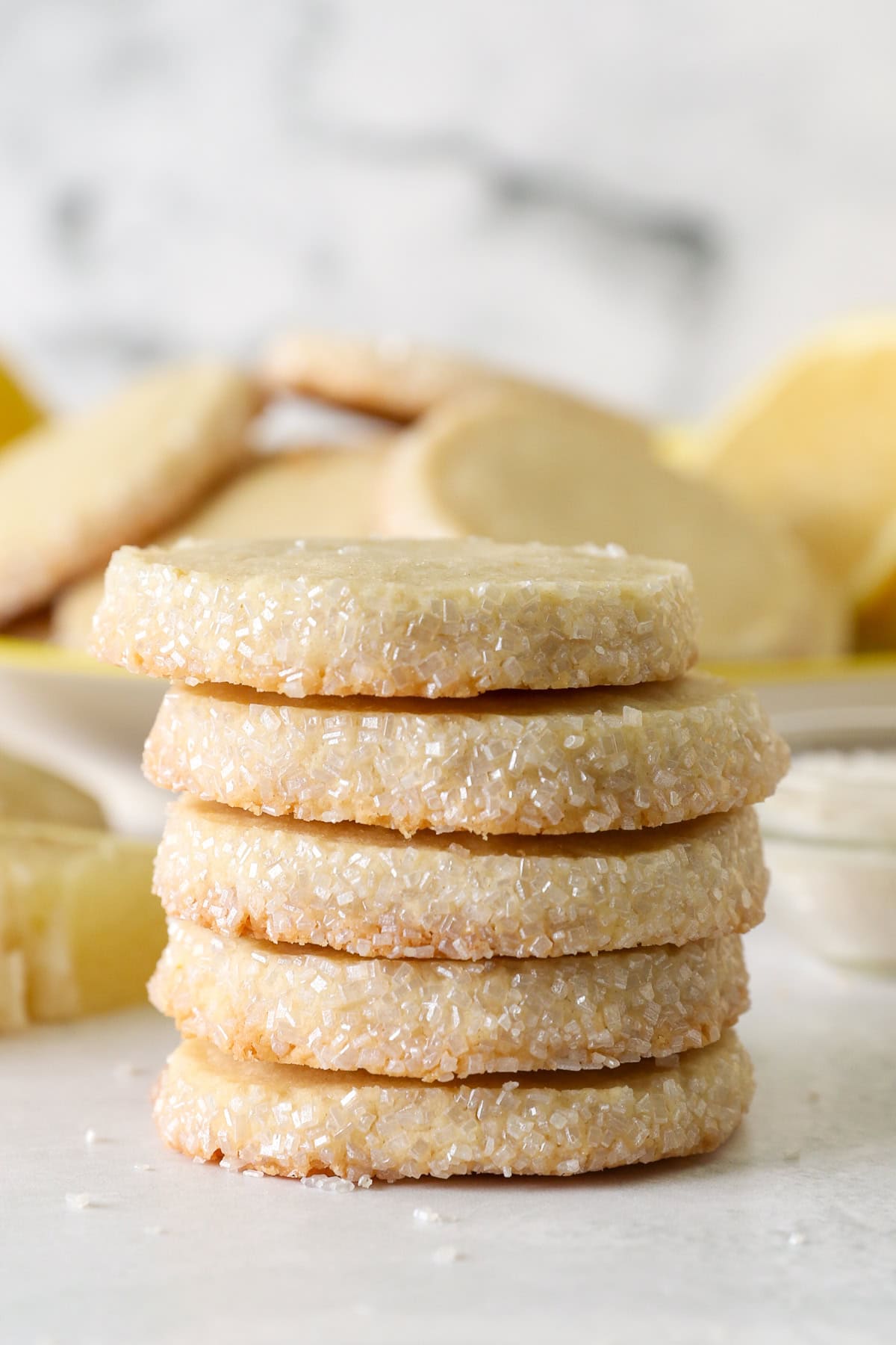 These slice-and-bake lemon shortbread cookies are crisp, buttery, and melt-in-your-mouth, rolled in sanding sugar for sweet, crunchy edges. A stack of lemon shortbread cookies.