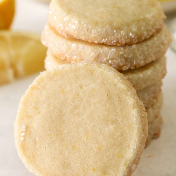 A lemon shortbread cookie leaning against a stack of cookies.