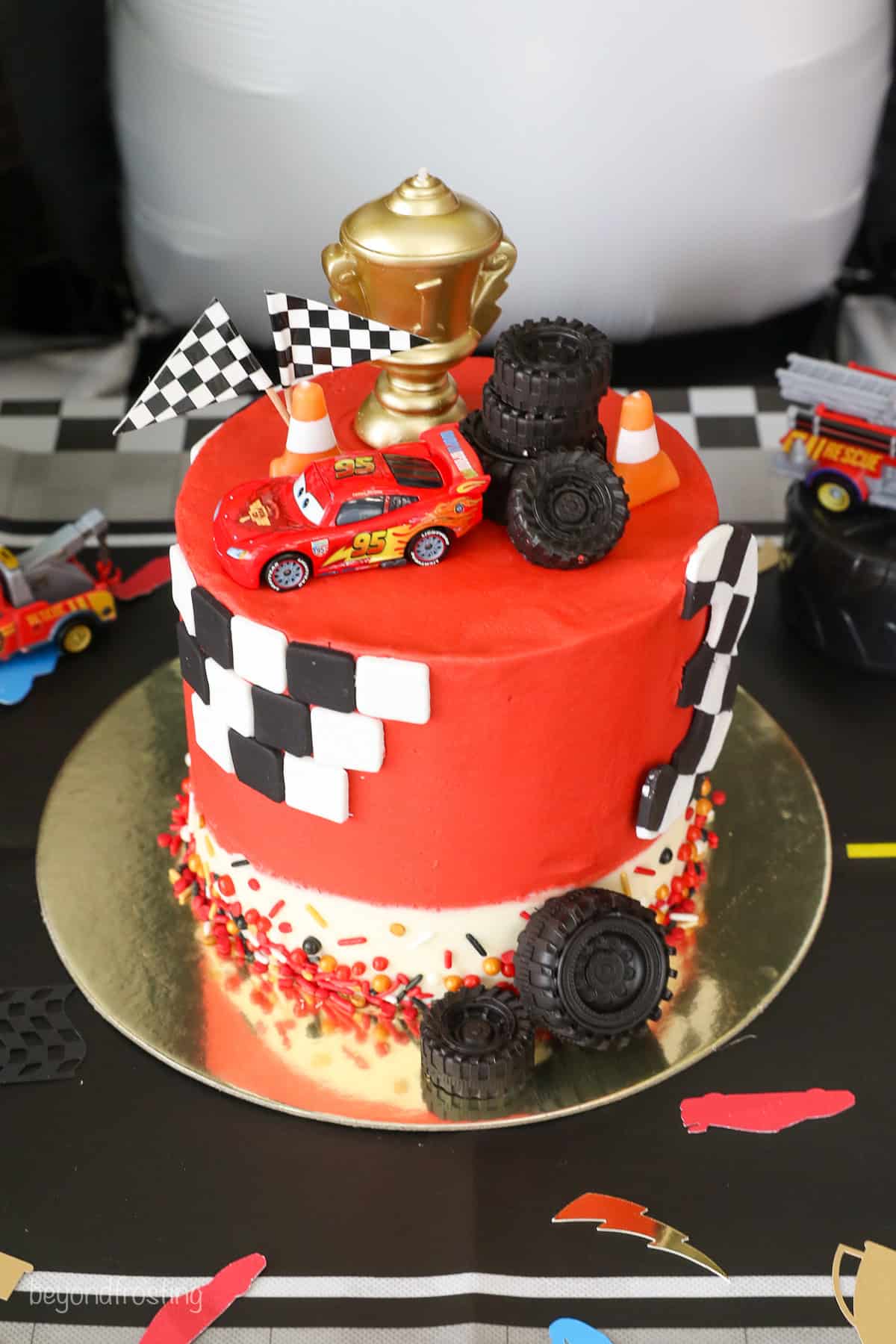 With racing-red frosting and just a little fondant, this Lightning McQueen layer cake is perfect for a kids’ Cars birthday party! A Lightning McQueen cake with racing themed decorations.
