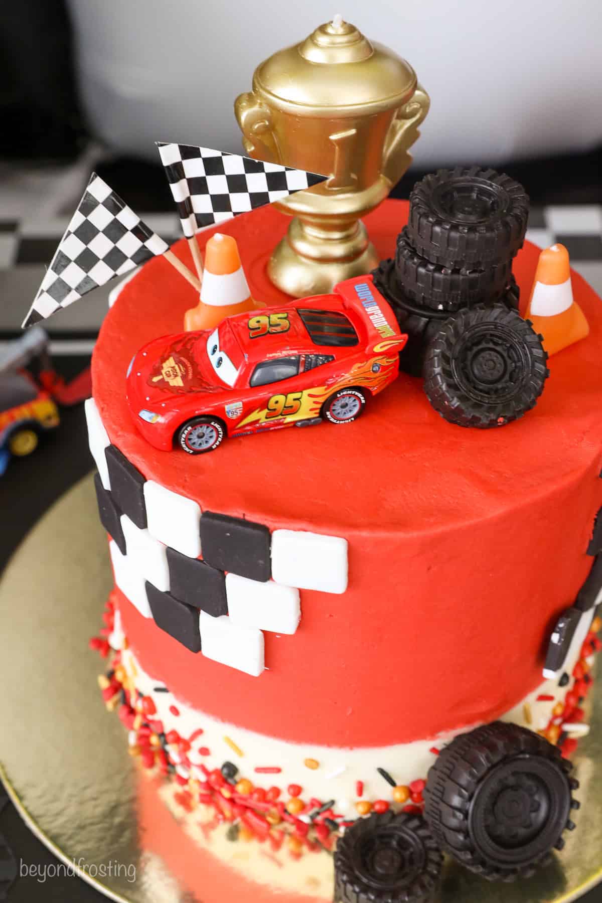 With racing-red frosting and just a little fondant, this Lightning McQueen layer cake is perfect for a kids’ Cars birthday party! A Lightning McQueen cake with racing themed decorations.