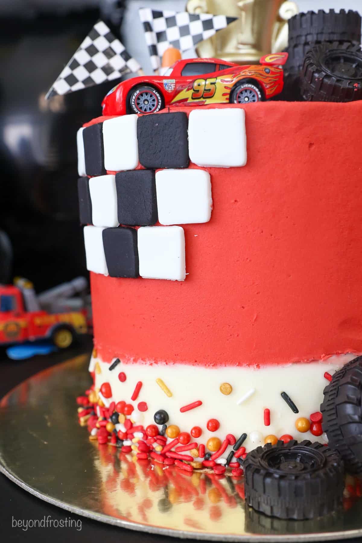 Close up of the side of a Lightning McQueen cake decorated with sprinkles and black and white checkered fondant.