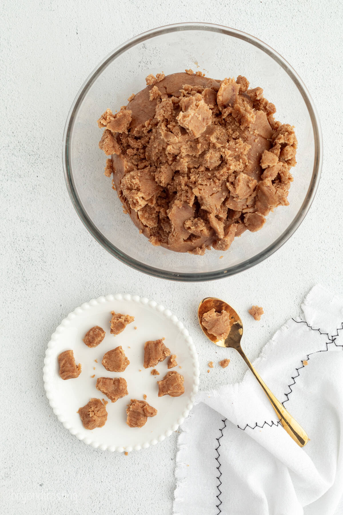This New York crumb cake is tender and buttery, piled high with a thick brown sugar cinnamon streusel that’s almost as thick as the cake. Cinnamon streusel in a glass bowl next to crumbles on a plate.