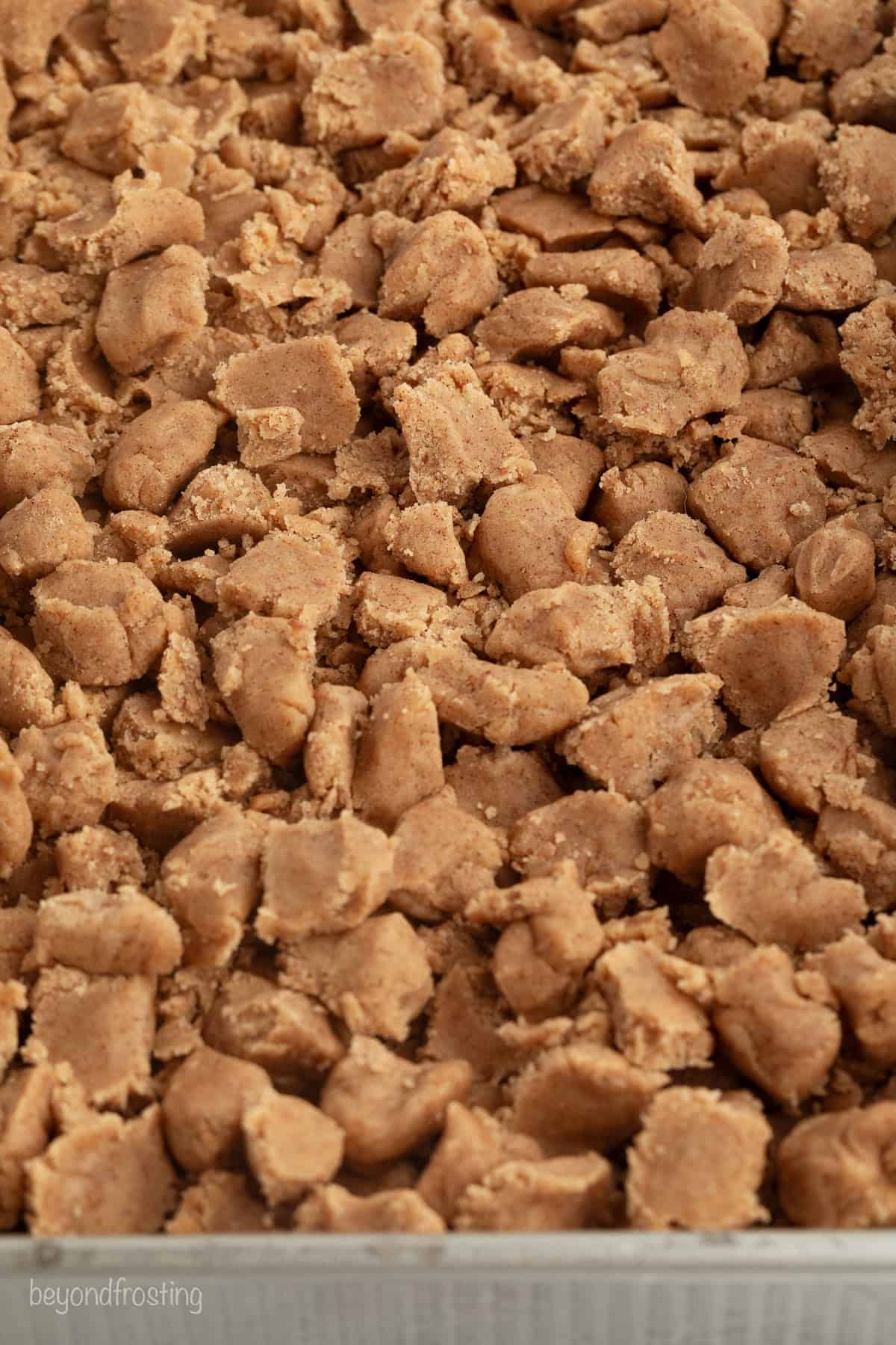 This New York crumb cake is tender and buttery, piled high with a thick brown sugar cinnamon streusel that’s almost as thick as the cake. Cinnamon streusel spread over crumb cake batter in a baking pan.