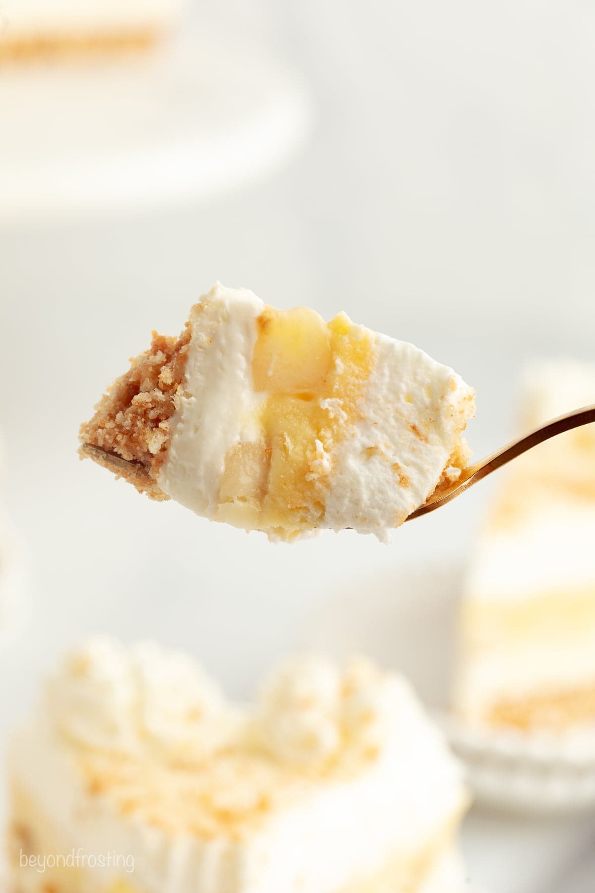 Make the best no-bake banana pudding cheesecake with creamy cheesecake filling, fresh banana slices, homemade pudding, and whipped cream. Close up of a forkful of no-bake banana pudding cheesecake.