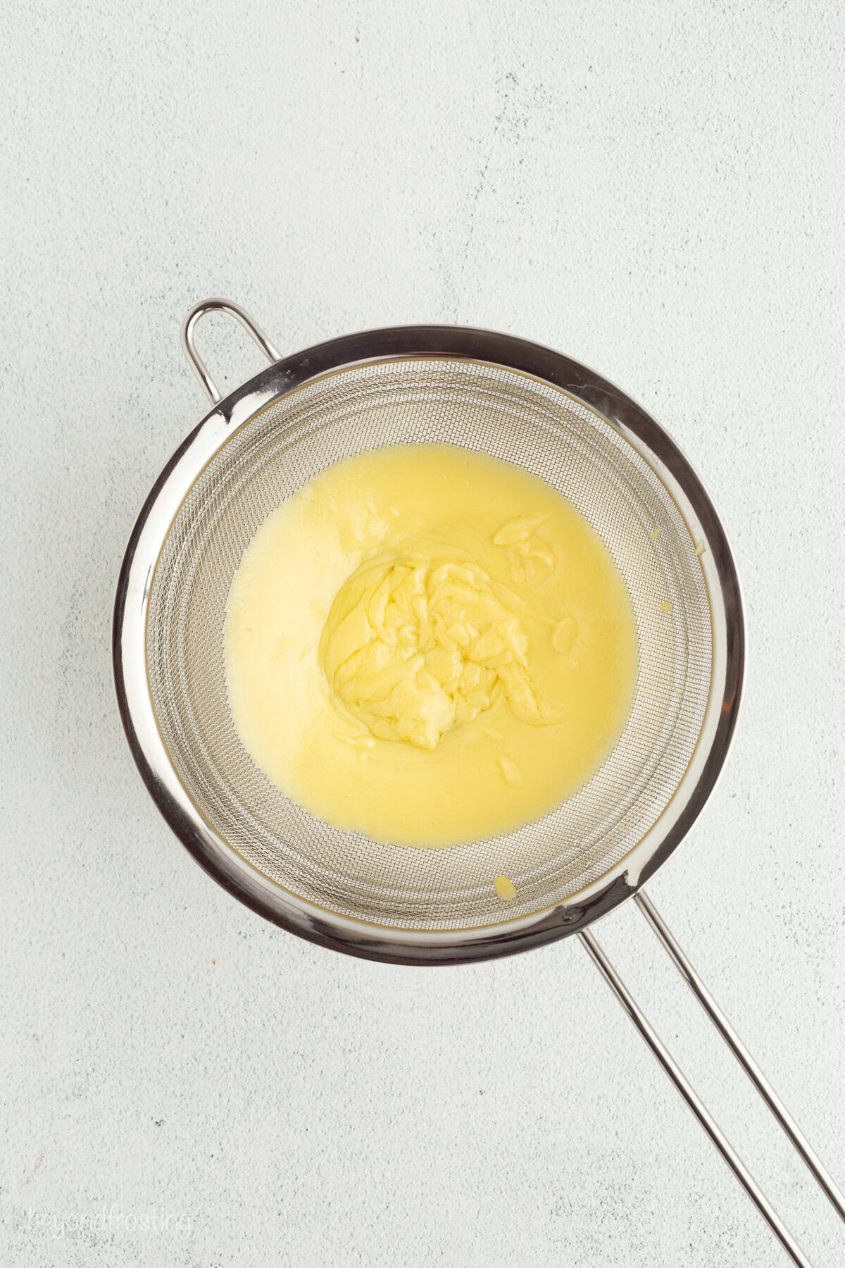 Make the best no-bake banana pudding cheesecake with creamy cheesecake filling, fresh banana slices, homemade pudding, and whipped cream. Straining the pudding through a fine mesh sieve.