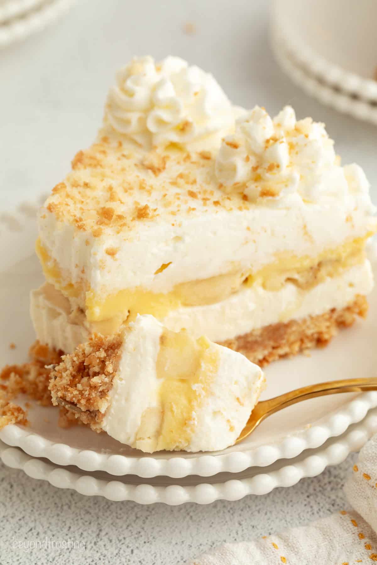 Make the best no-bake banana pudding cheesecake with creamy cheesecake filling, fresh banana slices, homemade pudding, and whipped cream. A slice of no-bake banana pudding cheesecake with a forkful next to it on a plate.