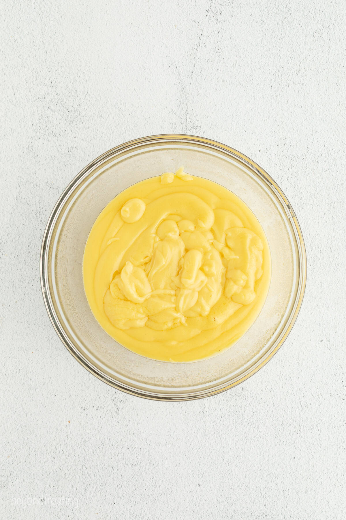 Make the best no-bake banana pudding cheesecake with creamy cheesecake filling, fresh banana slices, homemade pudding, and whipped cream. Strained pudding for banana pudding cheesecake in a glass bowl.