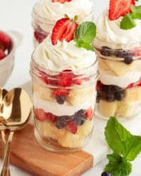 Mini trifles served parfait-style in jars with layers of pound cake, macerated berries, and whipped cream.