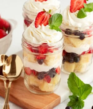 Mini trifles served parfait-style in jars with layers of pound cake, macerated berries, and whipped cream.