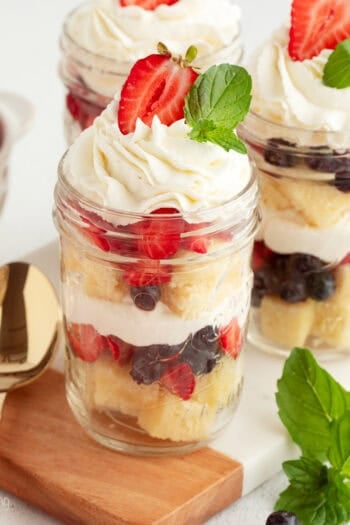 Mini trifles served parfait-style in jars with layers of pound cake, macerated berries, and whipped cream.