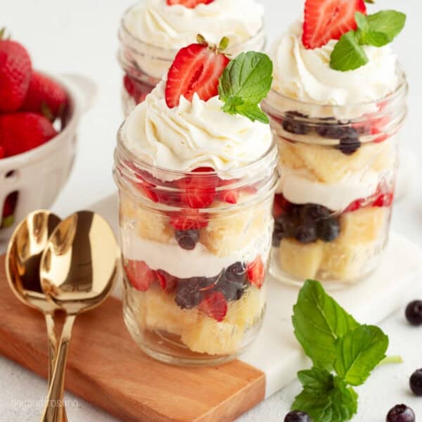 Mini trifles served parfait-style in jars with layers of pound cake, macerated berries, and whipped cream.