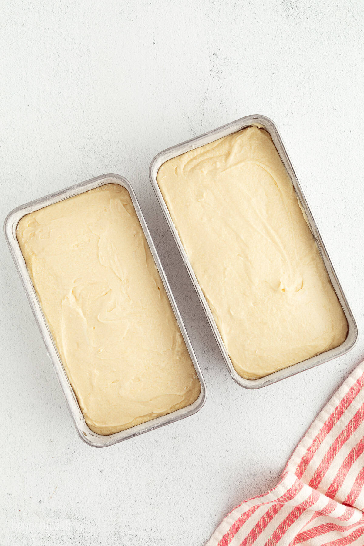 Mini trifles layer homemade pound cake, juicy berries, and mascarpone whipped cream into jars, parfait-style. Great for parties and holidays! Overhead view of two loaf pans filled with pound cake batter.