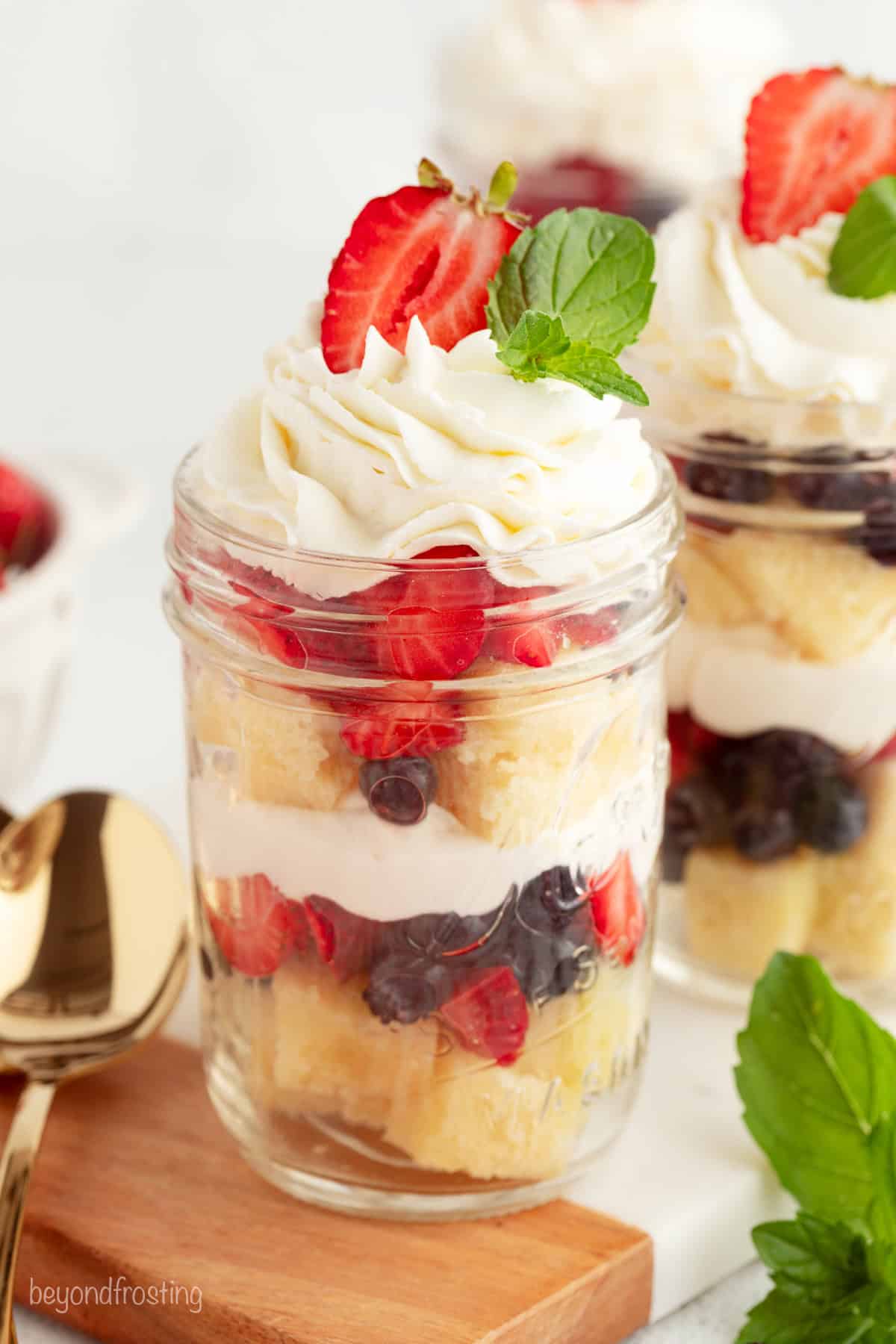 Mini trifles layer homemade pound cake, juicy berries, and mascarpone whipped cream into jars, parfait-style. Great for parties and holidays! Mini trifles served parfait-style in jars topped with swirls of whipped cream.