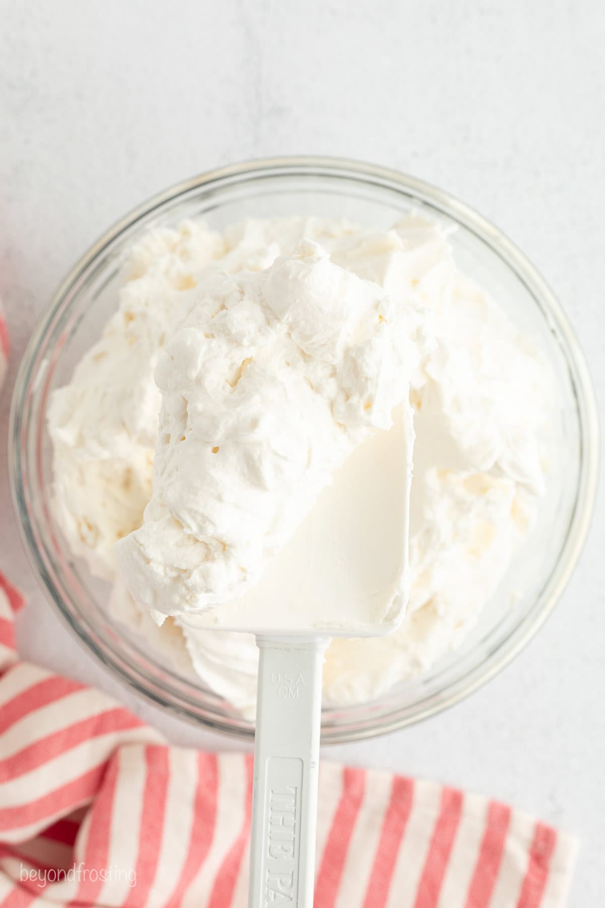 Mini trifles layer homemade pound cake, juicy berries, and mascarpone whipped cream into jars, parfait-style. Great for parties and holidays! A spatula with a scoop of mascarpone whipped cream held over a bowl.