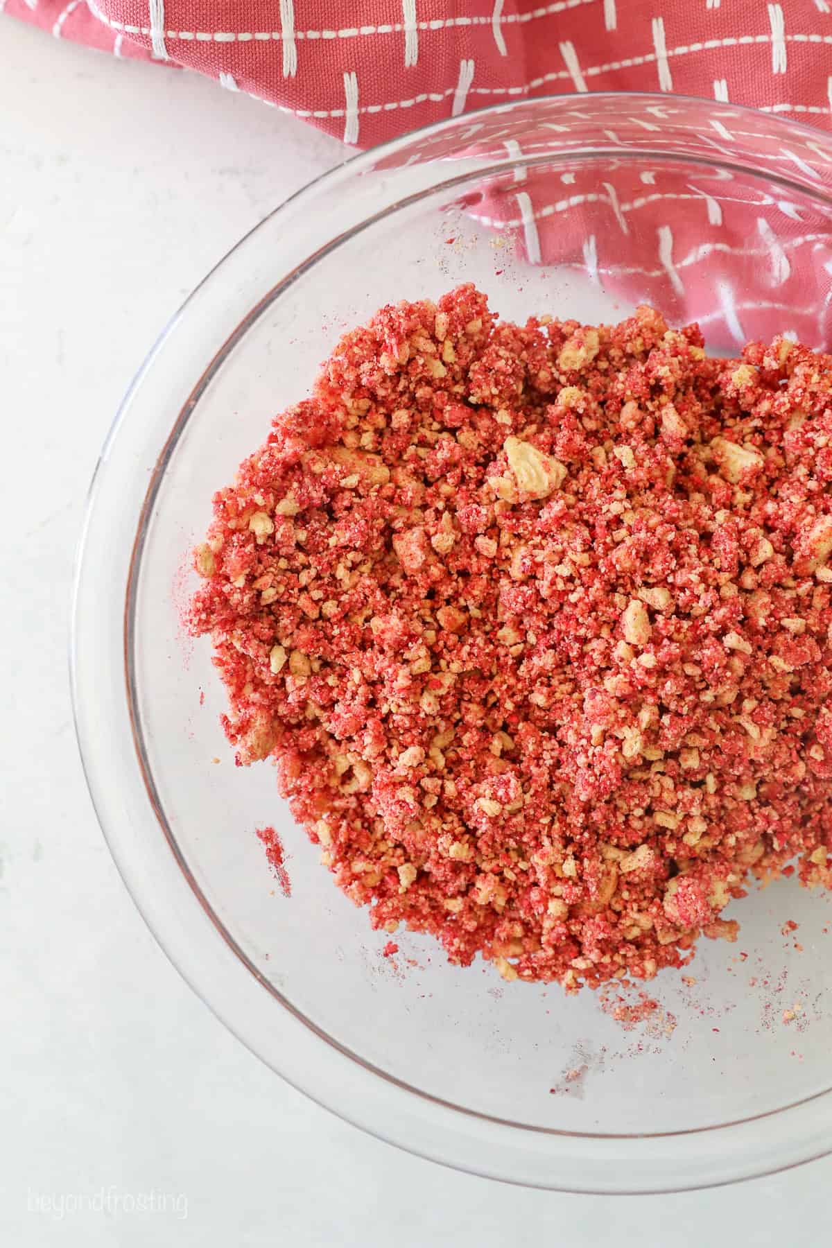 This strawberry crunch cake is a moist vanilla cake topped with creamy strawberry frosting and a crunchy strawberry and Golden Oreo crumb. Strawberry crunch in a bowl.