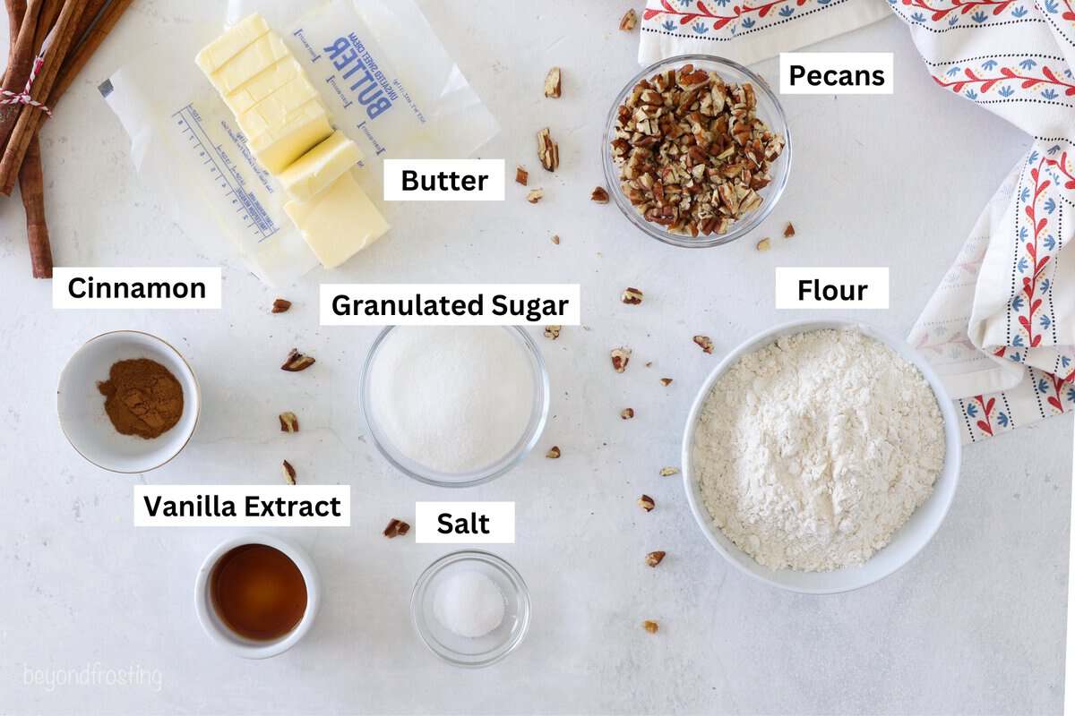 This easy pecan shortbread recipe makes soft, crumbly cookies filled with cinnamon, vanilla, and pecans. One bowl, no chilling or rolling! Ingredients for pecan shortbread cookies with text labels.