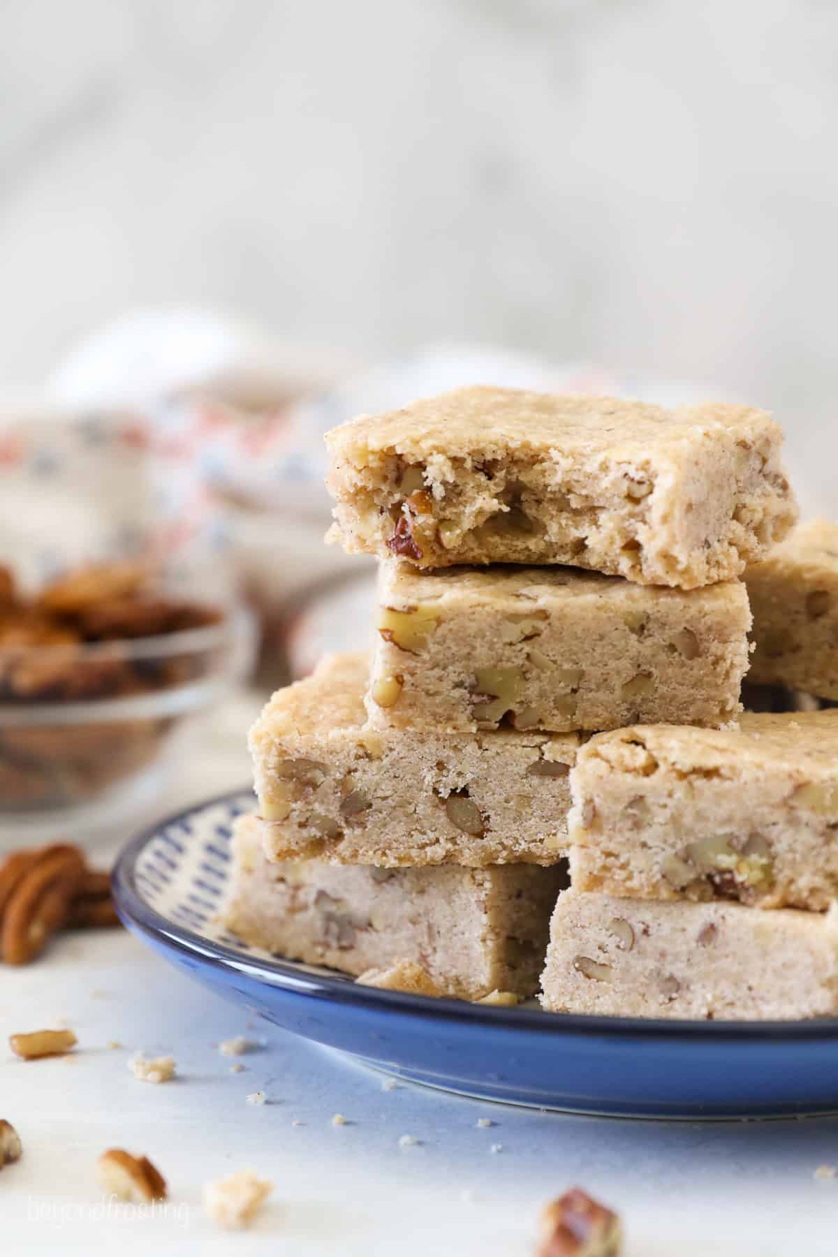 This easy pecan shortbread recipe makes soft, crumbly cookies filled with cinnamon, vanilla, and pecans. One bowl, no chilling or rolling! Pecan shortbread cookies stacked on a plate with a bite missing from the top cookie.