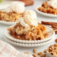A serving of apple dump cake topped with vanilla ice cream on a plate.