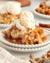 A serving of apple dump cake topped with vanilla ice cream on a plate.