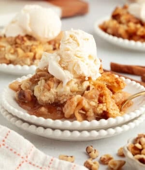 A serving of apple dump cake topped with vanilla ice cream on a plate.