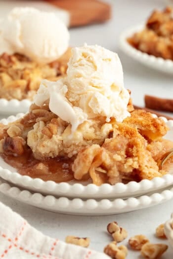 A serving of apple dump cake topped with vanilla ice cream on a plate.