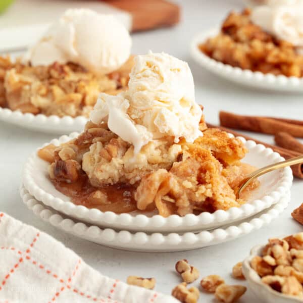 A serving of apple dump cake topped with vanilla ice cream on a plate.