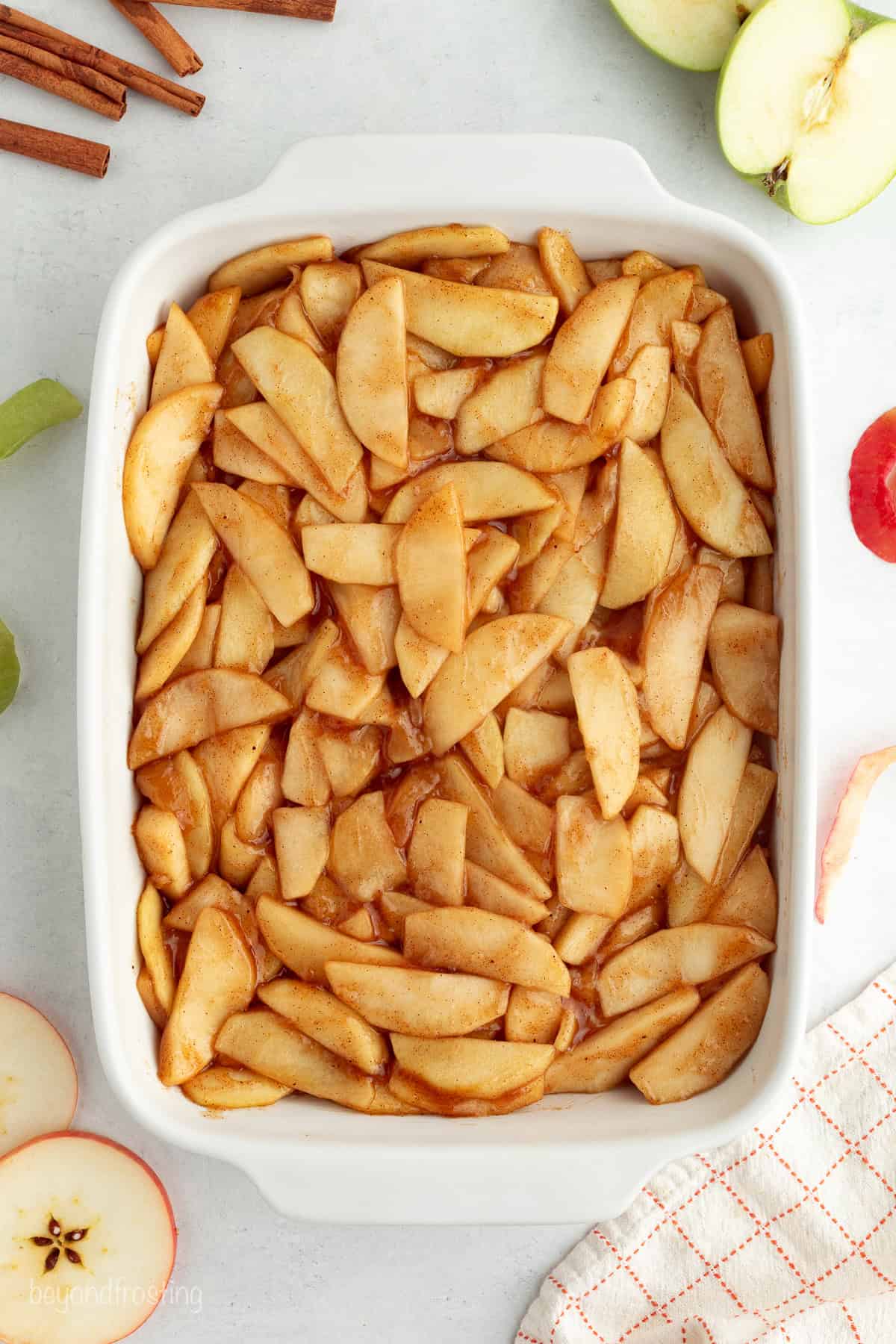 You don't need to stir this cozy apple dump cake! Dump juicy cinnamon apples into a cake pan, top with dry cake mix and butter, and bake. Cinnamon apple filling spread into a baking dish.