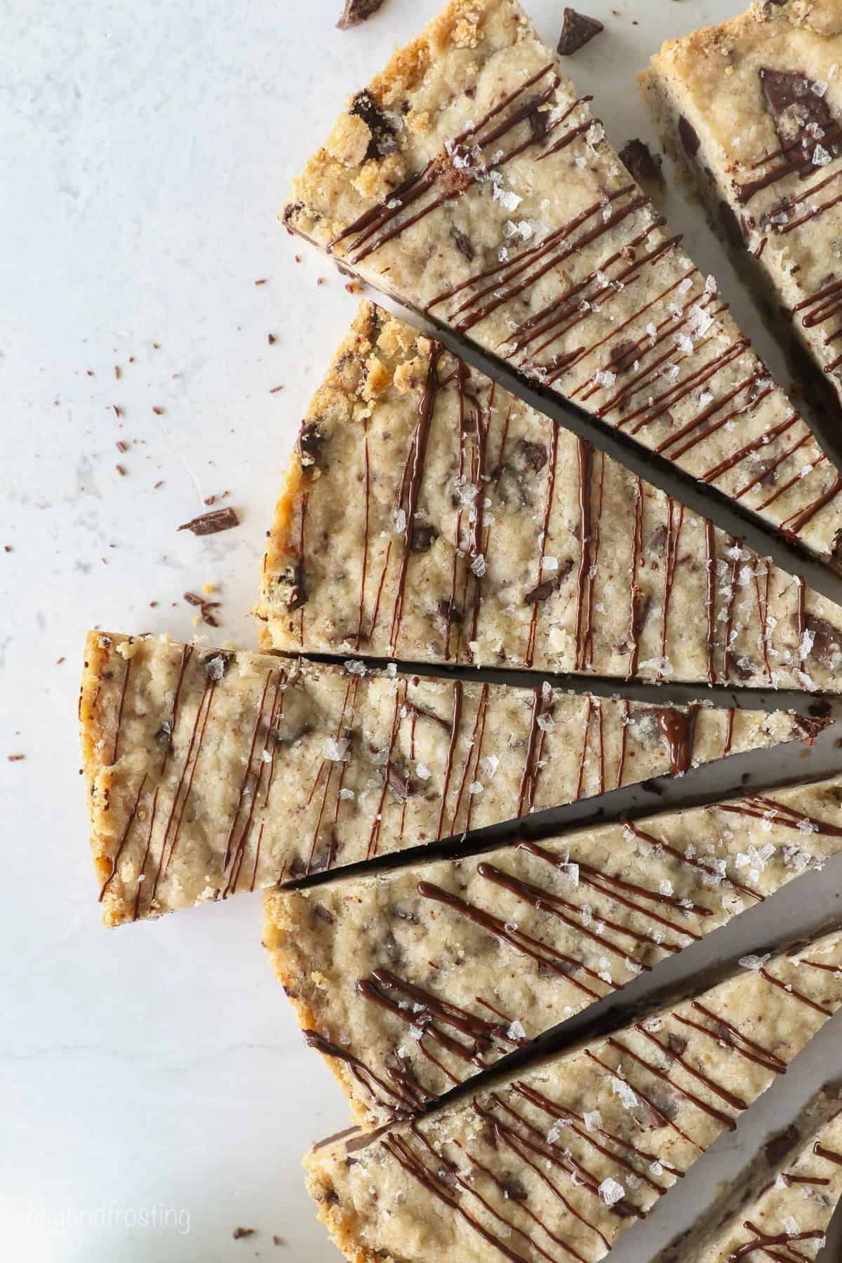 These classic, buttery shortbread cookies are filled with chopped chocolate and topped with a chocolate drizzle. Perfect for holiday baking! Overhead view of chocolate chip shortbread cookies cut into wedges and drizzled with chocolate.