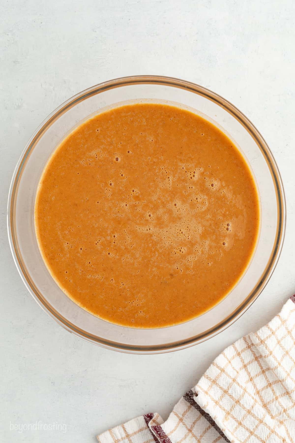 Fall pumpkin crunch cake is an easy, dump cake-style dessert with rich pumpkin filling and a buttery, crunchy cake mix layer with walnuts. Pumpkin filling mixture in a glass bowl.