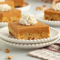 A slice of pumpkin crunch cake topped with whipped cream on a plate.
