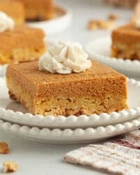 A slice of pumpkin crunch cake topped with whipped cream on a plate.