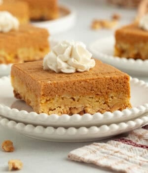A slice of pumpkin crunch cake topped with whipped cream on a plate.
