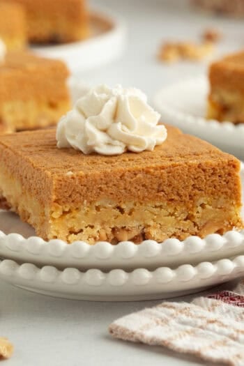 A slice of pumpkin crunch cake topped with whipped cream on a plate.