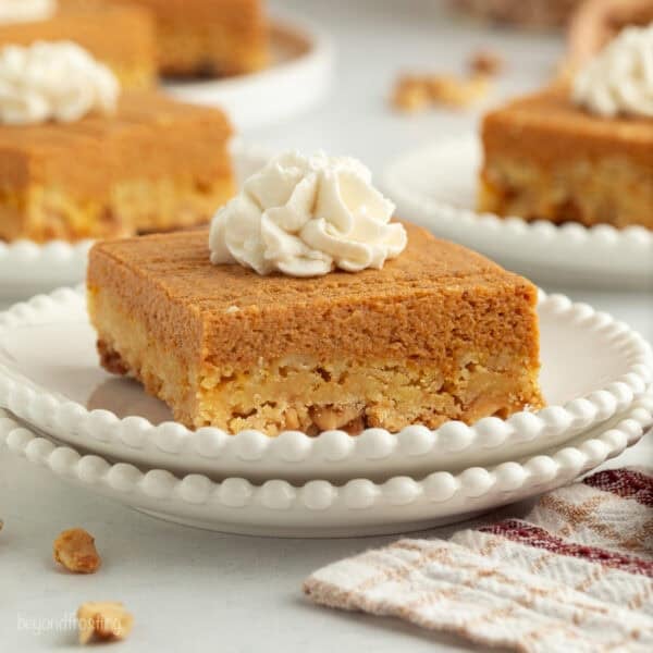 A slice of pumpkin crunch cake topped with whipped cream on a plate.