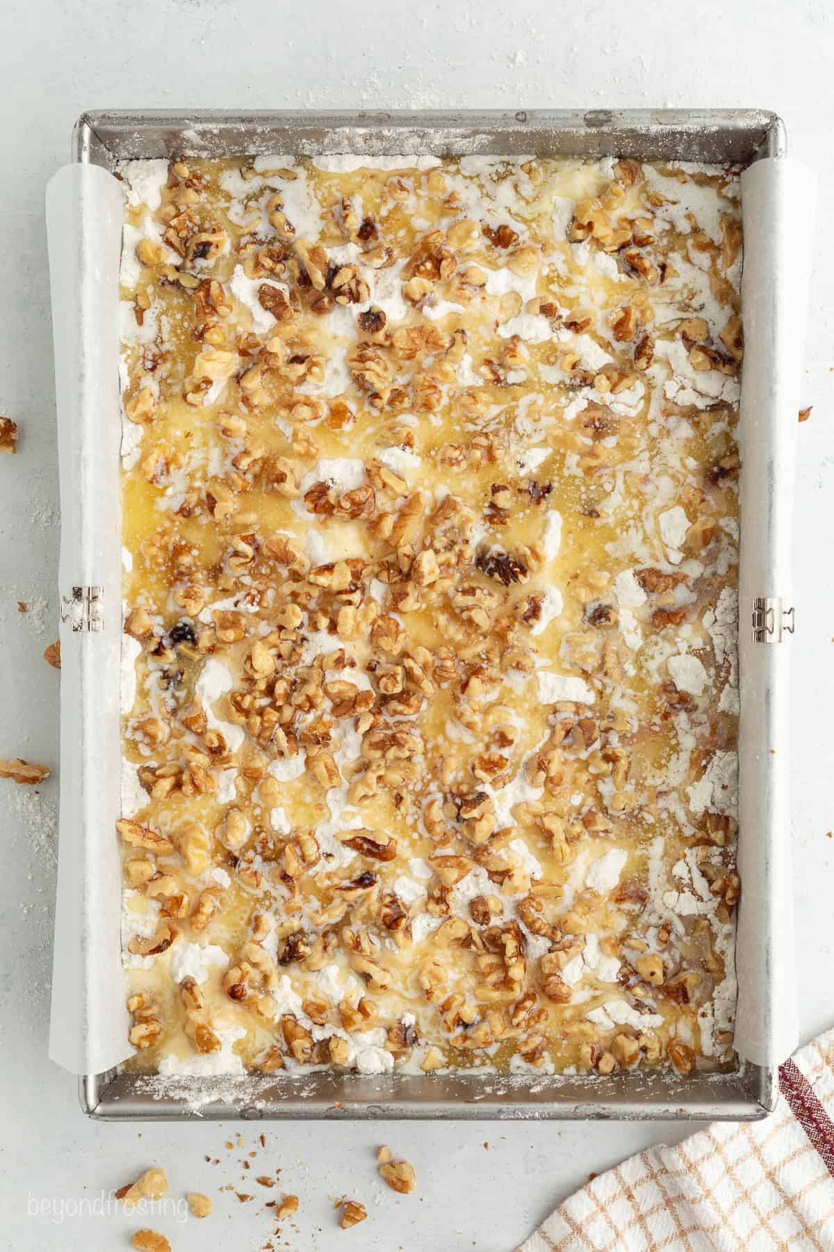 Fall pumpkin crunch cake is an easy, dump cake-style dessert with rich pumpkin filling and a buttery, crunchy cake mix layer with walnuts. Crunch ingredients scattered in a baking pan.
